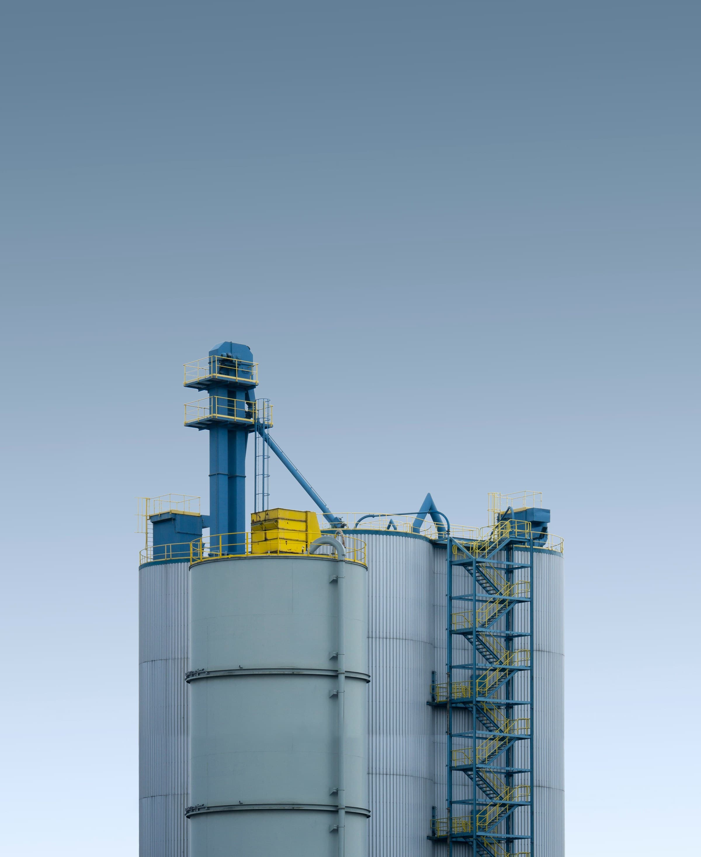 Silos industriels gris et bleus sous un vaste ciel